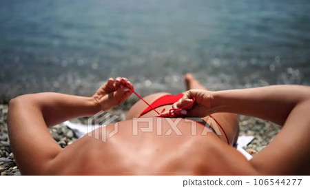 Woman taking red bikini off on beach for tan, lady stripping