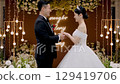 asian bride and groom exchanging vows at indoor wedding ceremony with floral and light decorations 129419706