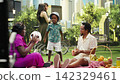 Parents and boy playing catch with soccer ball beside picnic basket, enjoying active sunny day in urban park with picnic blanket. Family bonding and playing ball game. Parents and boy playing catch with soccer ball beside picnic basket, enjoying active sunny day in urban park with picnic blanket. Family bonding and playing ball game. 142329461